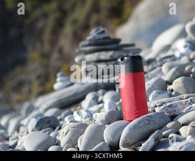 Vaso di bellezza rosso in plastica sullo sfondo di elementi naturali. Cosmetici e cura del viso e dei capelli. Modello per la progettazione. Prodotti ecocompatibili Foto Stock