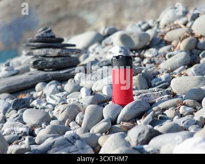 Vaso di bellezza rosso in plastica sullo sfondo di elementi naturali. Cosmetici e cura del viso e dei capelli. Modello per la progettazione. Prodotti ecocompatibili Foto Stock