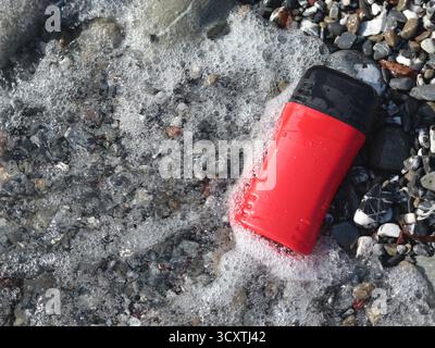 Vaso di bellezza rosso in plastica sullo sfondo di elementi naturali. Cosmetici e cura del viso e dei capelli. Modello per la progettazione. Prodotti ecocompatibili Foto Stock