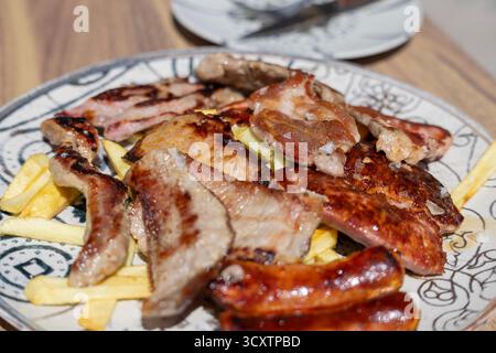 Grigliata mista di parrillada iberica con tagli di maiale, salsicce e chorizo su un piatto caldo, tradizionale piatto spagnolo barbecue dall'Andalusia, Spagna Foto Stock