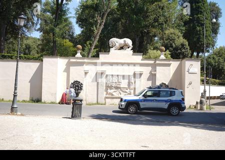 Un SUV "polizia Roma capitale" parcheggiato vicino a una parete classica con una statua di leone, adiacente ai giardini di Villa Borghese a Roma, Italia. Foto Stock
