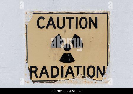 Cartello di attenzione avvertenza rischio radiazioni visualizzato su una parete intemprata Foto Stock