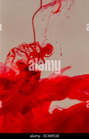 Inchiostro rosso brillante che scorre in acqua Foto Stock