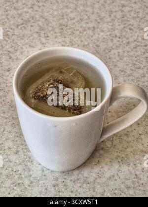tè alle erbe confezionato estratto in una tazza Foto Stock