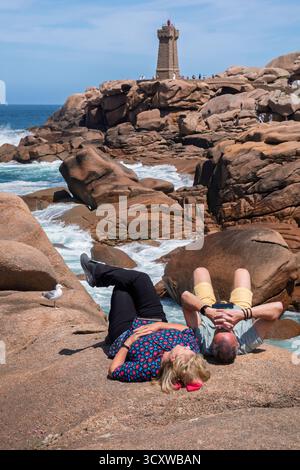Turisti che giacciono sulle rocce al Côte de Granit Rose vicino al faro "Phare de Men Ruz", Ploumanac'h, Côtes-d'Armor, Bretagna Foto Stock