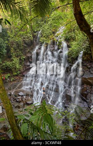 Un uomo posa per una foto alla cascata di Kanto lampo a Gianyar, Bali, Indonesia. Foto Stock