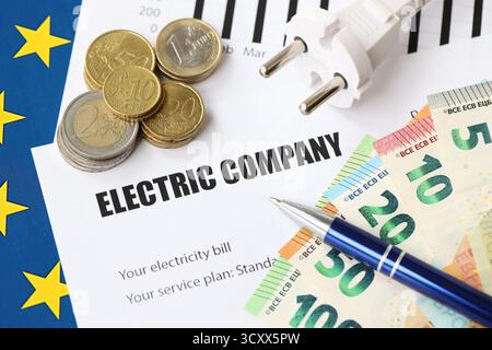 Banconote e monete in euro dell'unione europea con bolletta dell'elettricità sul tavolo da vicino Foto Stock