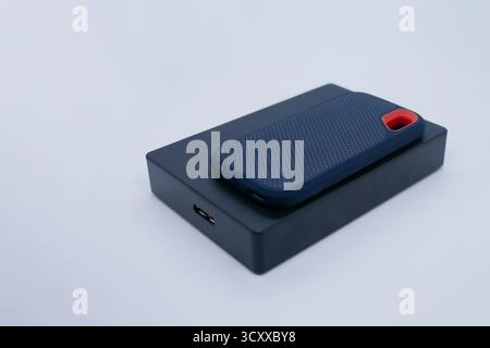 Primo piano di due dischi rigidi esterni, un'unità SSD compatta e un'unità HDD più grande, posizionati su uno sfondo bianco. Concetti tecnici, dati, backup e hardware. Foto Stock