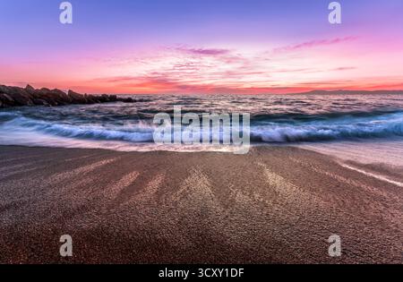 Una colorata alba sull'Oceano con Un'onda dolce che si infrangono sulla costa Foto Stock