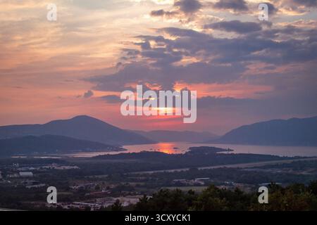 Tramonto nella baia di Cattaro, Montenegro. Una vista mozzafiato di una città costiera annidata tra montagne torreggianti. Foto Stock