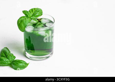 Bevanda liquida di clorofilla verde. Bicchiere di acqua di Chrorophyll con foglie di basilico su sfondo bianco, copia spazio. Alimentazione sana, stile di vita pulito, disintossicazione Foto Stock