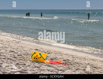 giocattoli da spiaggia sulla spiaggia di santa rosa con persone in piedi in acqua sullo sfondo Foto Stock