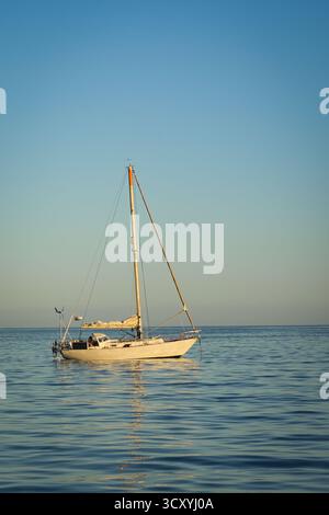 Barca a vela tranquillamente all'ancora su un mare calmo sotto un cielo sereno, luce dorata e ampio spazio per le copie, Isole Canarie, Oceano Atlantico Foto Stock