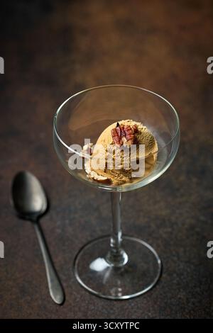 paletta per gelato al caramello con noci servita in vetro su sfondo marrone scuro Foto Stock
