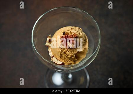 paletta per gelato al caramello con noci servita in vetro su sfondo marrone scuro Foto Stock