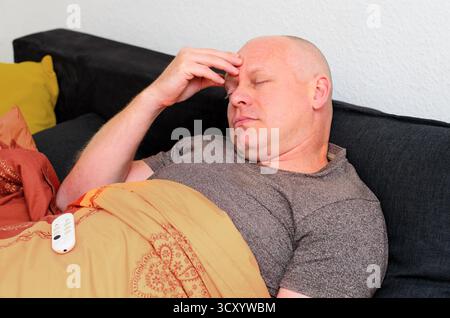 Uomo di mezza età che soffre di grave mal di testa o sintomi influenzali a casa Foto Stock