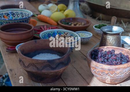 Un tavolo rustico in legno con varie verdure fresche, frutta, cereali e noci in ciotole di ceramica per cucinare la cucina tradizionale Foto Stock
