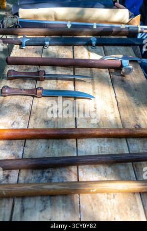 Antica collezione di armi medievali su un tavolo di legno per rievocazioni storiche e simulazioni di battaglia Foto Stock