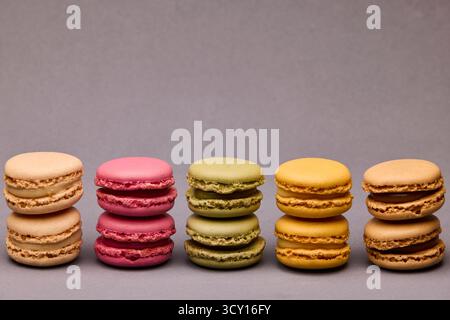 Set di cinque macaron colorati disposti in pila alternata su una superficie grigia. Immagine da dessert in studio bilanciata ed elegante per uso commerciale. Foto Stock