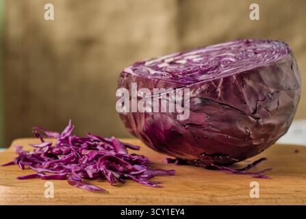 Un primo piano di un mucchio di cavolo rosso viola appena tritato su un tagliere di legno Foto Stock