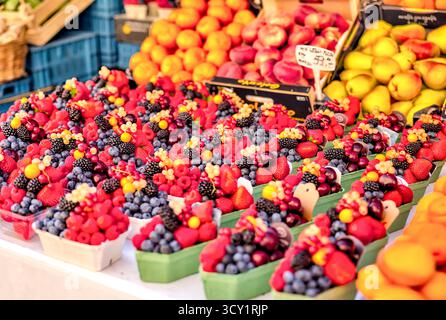 Frutti di bosco freschi e frutta confezionati in cartoni di carta presso un mercato di Praga, Repubblica Ceca, con prodotti locali e colori estivi. Foto Stock
