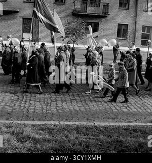 Una suggestiva foto d'archivio del 7 novembre 1974 cattura lo spirito di una parata dell'anniversario della rivoluzione d'ottobre a Sloviansk, RSS Ucraina. Una grande colonna di manifestanti, comprese famiglie con bambini, marcia lungo una strada acciottolata. I partecipanti portano bandiere sovietiche, ritratti di leader politici, striscioni con slogan come "Glory to the Heroes of Labor" e palloncini festivi. Questa immagine è un vivido documento di una grande festa di stato e della vita pubblica di un pacifico Donbas prima della guerra Foto Stock