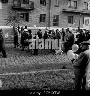 Una suggestiva foto d'archivio del 7 novembre 1974 cattura lo spirito di una parata dell'anniversario della rivoluzione d'ottobre a Sloviansk, RSS Ucraina. Una grande colonna di manifestanti, comprese famiglie con bambini, marcia lungo una strada acciottolata. I partecipanti portano bandiere sovietiche, ritratti di leader politici, striscioni con slogan come "Glory to the Heroes of Labor" e palloncini festivi. Questa immagine è un vivido documento di una grande festa di stato e della vita pubblica di un pacifico Donbas prima della guerra Foto Stock