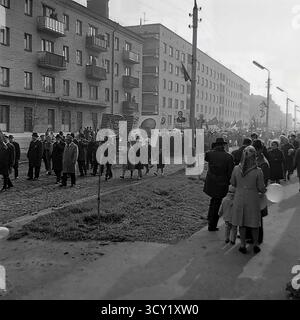 Una suggestiva foto d'archivio del 7 novembre 1974 cattura lo spirito di una parata dell'anniversario della rivoluzione d'ottobre a Sloviansk, RSS Ucraina. Una grande colonna di manifestanti, comprese famiglie con bambini, marcia lungo una strada acciottolata. I partecipanti portano bandiere sovietiche, ritratti di leader politici, striscioni con slogan come "Glory to the Heroes of Labor" e palloncini festivi. Questa immagine è un vivido documento di una grande festa di stato e della vita pubblica di un pacifico Donbas prima della guerra Foto Stock