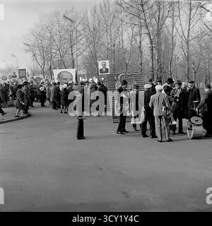 Una suggestiva foto d'archivio del 7 novembre 1974 cattura una dimostrazione su larga scala per l'anniversario della Rivoluzione d'ottobre a Sloviansk. Colonne di cittadini, comprese famiglie e una banda di ottoni, marciano attraverso le strade e la piazza centrali della città. Portano con orgoglio bandiere sovietiche, striscioni e grandi ritratti di Lenin e di altri leader politici. Questa immagine è un vivido documento di una grande festa di stato, che mostra lo spirito collettivo e la vita pubblica di un pacifico Donba prima della guerra Foto Stock