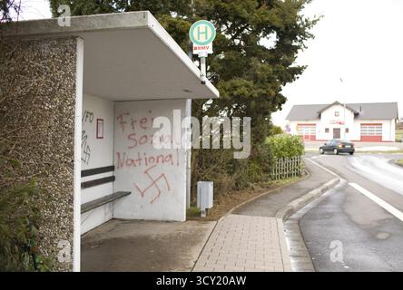 Graffiti nazionalsocialisti DEU Caan sul muro di una fermata dell'autobus a Caan, un villaggio vicino alla città di Neuwied. Sullo sfondo, i mezzi antincendio Foto Stock