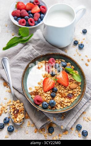 Ciotole di muesli con fragole fresche, mirtilli, lamponi, yogurt, noci, e miele per una colazione sana Foto Stock