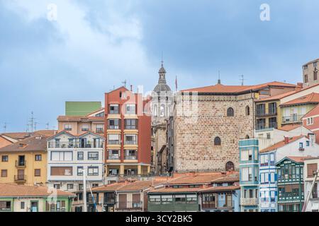 Vista panoramica dello storico lungomare di Bermeo che mostra la torre della chiesa di Santa Eufemia e le vivaci case tradizionali con facciate colorate Foto Stock