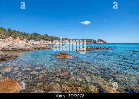 Vista panoramica della spettacolare costa della Costa Brava, caratterizzata da acque turchesi cristalline, rocce aspre in primo piano e tradizionali bianche Foto Stock