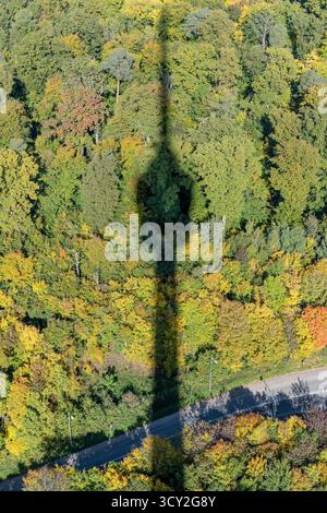 Paesaggio urbano aereo con l'ombra di un'alta torre sul legno autunnale sottostante, girato con la luce brillante della caduta dalla torre della televisione di Stoccarda, Germania Foto Stock