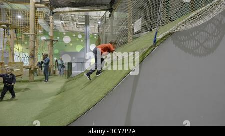 Arrampicate e scivolate su un pendio artificiale in un parco giochi al coperto. Creatività Foto Stock