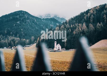 Chiesa di San Giovanni nella valle di Ranui Funes, Dolomiti, Italia, circondata da alberi autunnali. Foto Stock