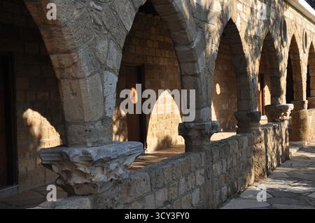 Bellissimi archi in pietra con disegni intricati delimitano un passaggio pedonale nella città vecchia. La luce calda del sole della sera proietta ombre morbide, aggiungendo un tocco alla torta Foto Stock
