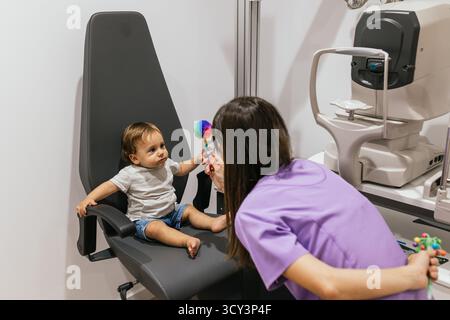 Optometrista che esegue l'esame oculistico sul bambino in clinica Foto Stock