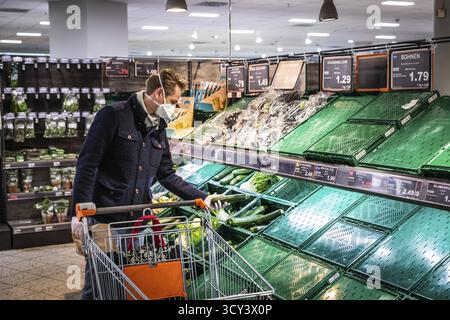 DEU Germany Germany Berlin Shoppers che indossano maschere protettive presso uno stand di frutta in un supermercato Foto Stock