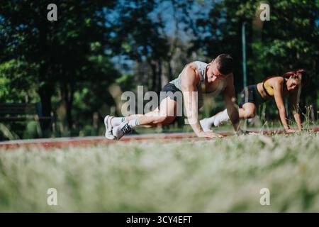Coppia in forma fisica che si allena all'aperto eseguendo esercizi in un parco naturale Foto Stock