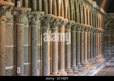 Le storiche colonne in pietra e gli archi del chiostro dell'abbazia di Mont Saint Michel, che mostrano la bellezza architettonica medievale e l'intricata artigianato. Foto Stock