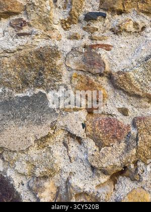 Parete in pietra ruvida con motivo testurizzato, ideale per gli sfondi Foto Stock