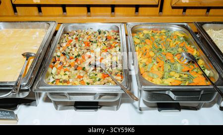 Un vivace buffet con vassoi assortiti pieni di colorate verdure cotte. Perfetto per eventi di catering, con piatti vegetariani sani Foto Stock