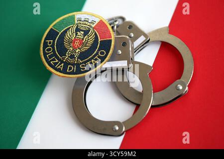 KIEV, UCRAINA - 6 SETTEMBRE 2025 polizia di Stato italiana patch e manette sulla bandiera nazionale primo piano Foto Stock