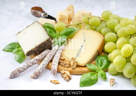 Stuzzichini di formaggio e uva serviti su un piatto di legno Foto Stock