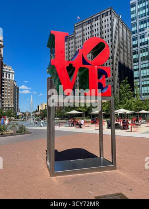Una grande scultura dell'amore è in mostra in un parco cittadino. La scultura è realizzata in metallo ed è circondata da diversi tavoli e sedie. Il parco è pieno Foto Stock