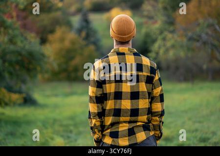 Ritratto di un giovane con la barba in un cappello arancione in un paesaggio autunnale. Foto Stock