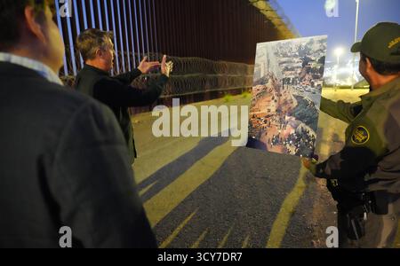 Rodney S. Scott, Commissario delle dogane e della protezione delle frontiere degli Stati Uniti, a sinistra, fa un gesto verso una foto storica che mostra una grossa barriera di confine lungo l'attuale muro di confine tra Stati Uniti e Messico durante un tour di confine vicino a San Diego, California, 18 agosto 2025. Foto CBP di Jaime Rodriguez Foto Stock