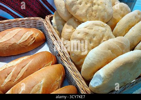 Una selezione di pane di frumento appena sfornato riposa in cesti rustici in un mercato locale. Il pane varia nella forma e nelle dimensioni, mostrando artigianato artigianale Foto Stock