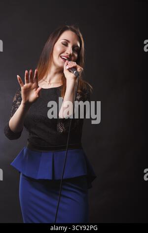 Il cantante in abito con microfono in mani canta in studio Foto Stock